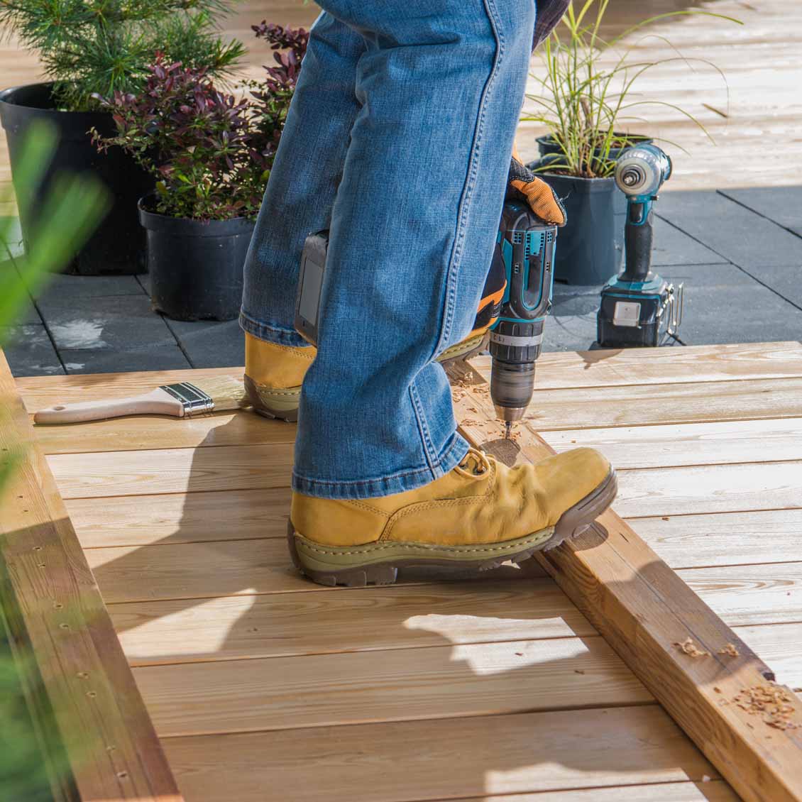 Adult Drilling Wooden Board Outdoors During the Daytime