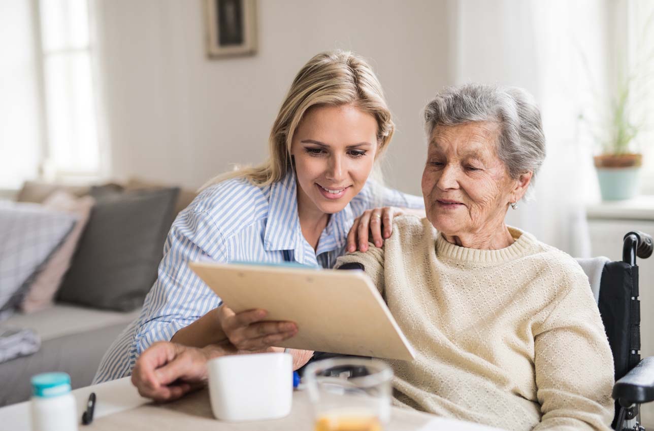 Woman with senior woman reading clipboard at home