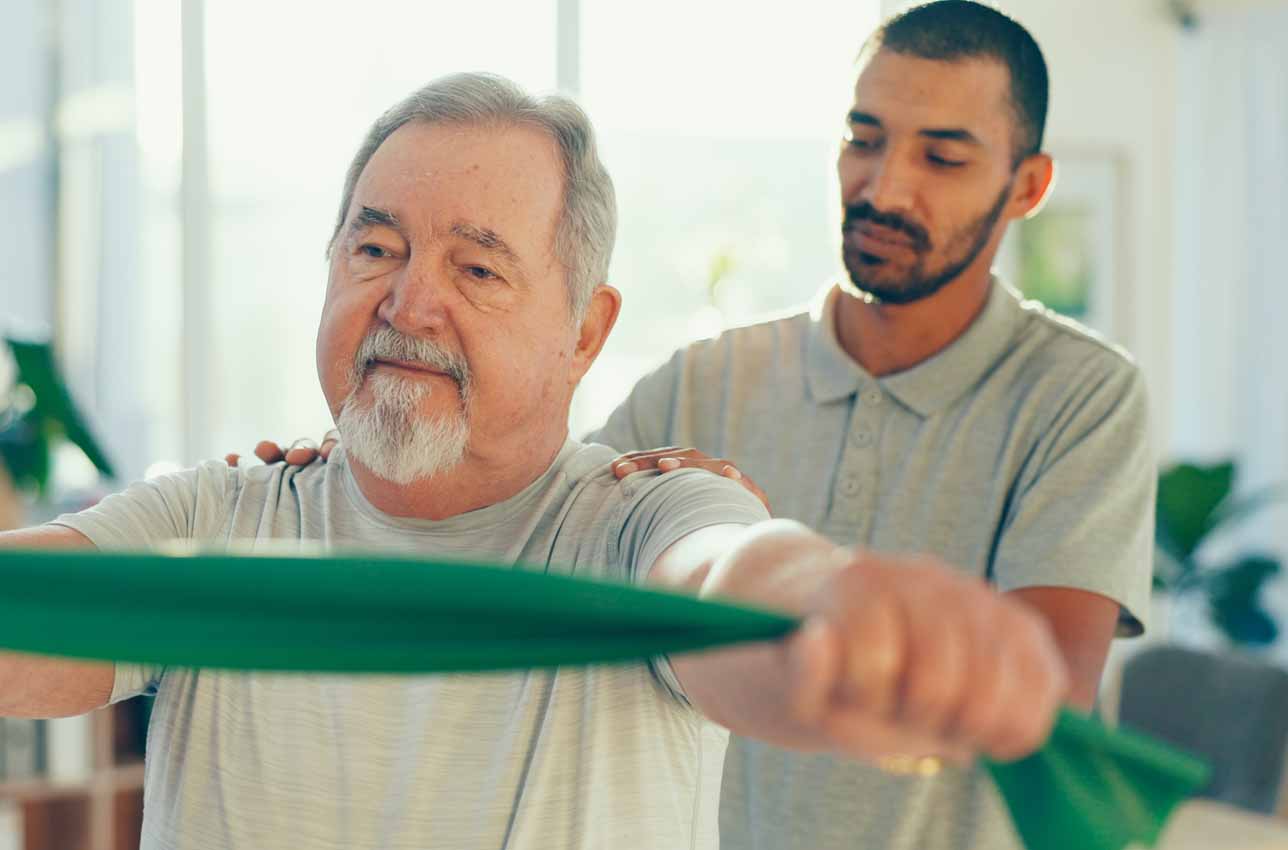 Senior adult exercising with therapist using resistance bands