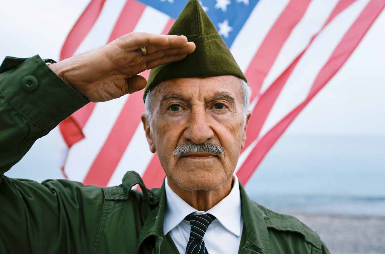 Senior man saluting with American flag backdrop